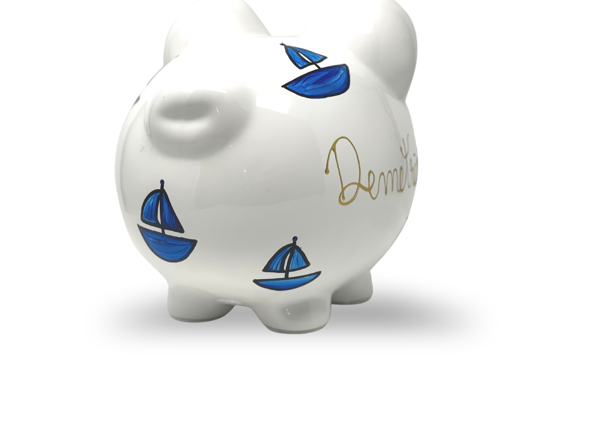 White piggy bank with blue sailboat designs and name written on a white background
