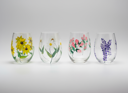 Four stemless wine glasses with floral designs on a white background