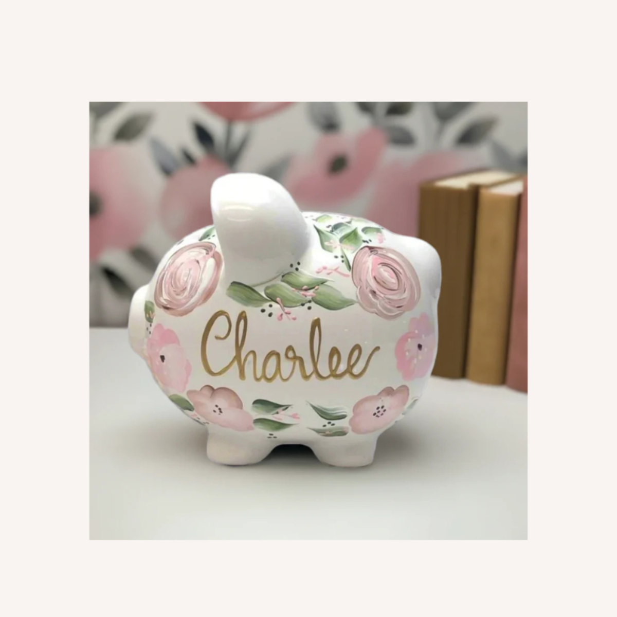 Floral-patterned piggy bank with 'Charlee' on a white surface