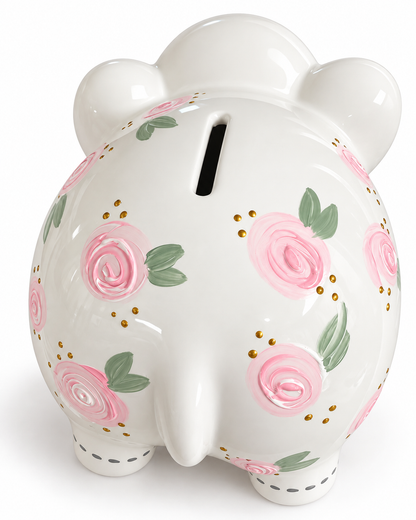 A glossy white pig-shaped piggy bank decorated with pink roses, green leaves, and small gold dots, shown on a clean white background.