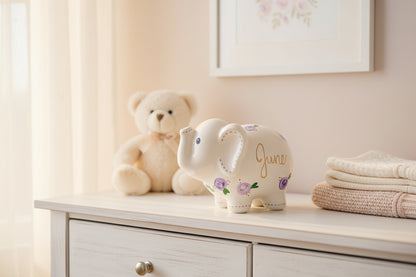 Hand-painted ceramic elephant with 'June' and floral designs on a light background.