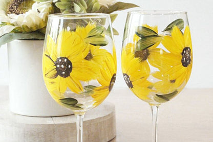 Two wine glasses with sunflower designs on a light background